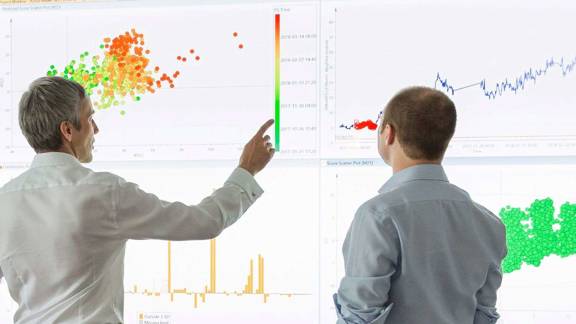 Two OPEX employees analysing data on a large screen.