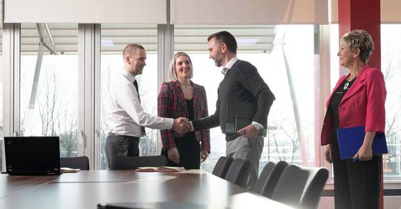 Work colleagues meet with a customer in a boardroom.